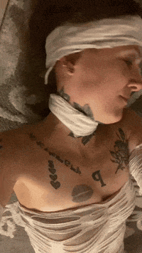 a woman wrapped in bandages has a tattoo on her chest that says ' i love you '