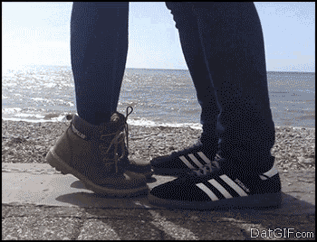 a person wearing a pair of caterpillar boots stands next to a person wearing adidas shoes