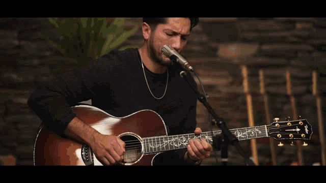 a man playing an acoustic guitar and singing into a microphone
