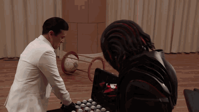 a man in a white suit stands next to a robot