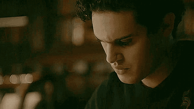 a close up of a young man 's face in a dark room with a blurry background .