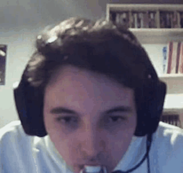 a young man wearing headphones and a microphone looks at the camera