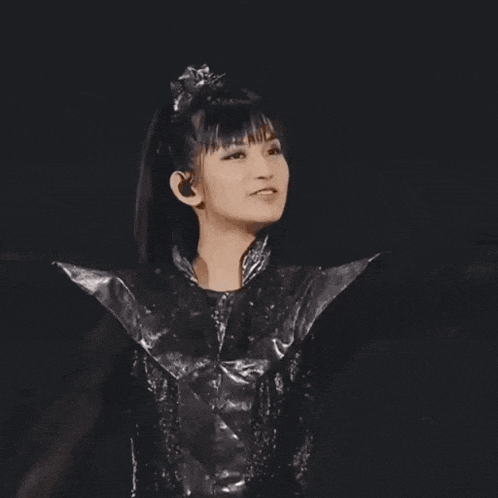 a woman in a black and silver outfit is holding her nose