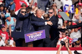 donald trump is being hugged by a group of people at a campaign rally .