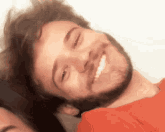 a man with a beard is smiling with his eyes closed