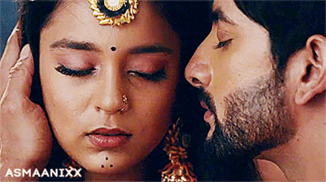 a close up of a man kissing a woman on the forehead .