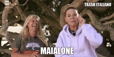 two women are sitting under a tree and one of them is laughing .