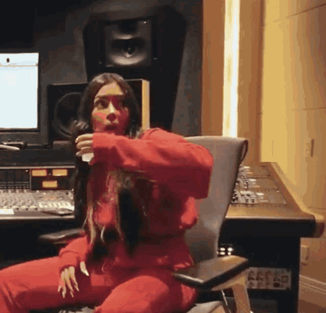 a woman in a red outfit is sitting in a chair in front of a desk with the number 26 on it