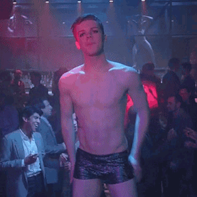 a shirtless man is standing in front of a crowd in a club