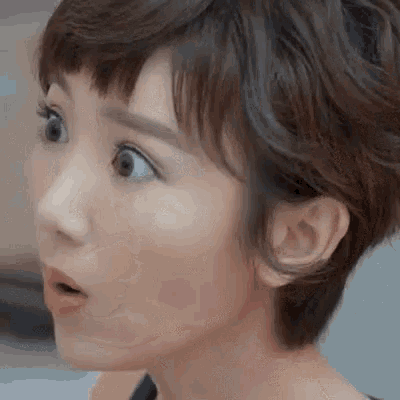 a close up of a woman 's face with her mouth open and a surprised look on her face .
