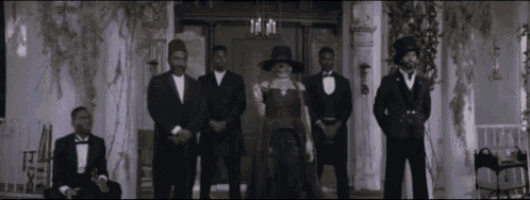 a group of men in tuxedos and hats standing in front of a building