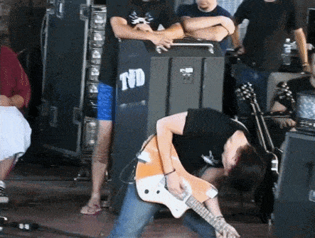 a man playing a guitar in front of a tnd shirt