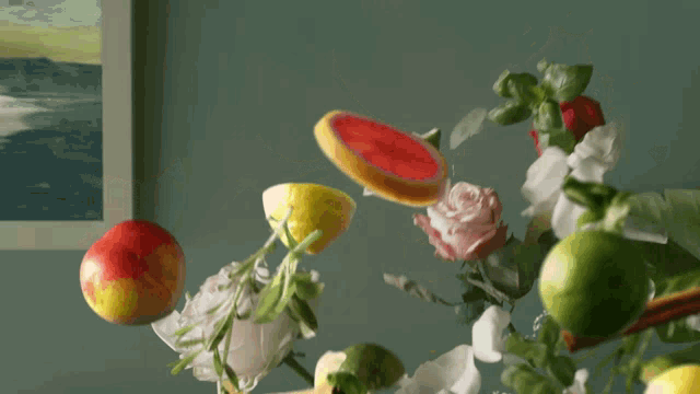 a painting hangs on a wall above a vase of fruit and flowers