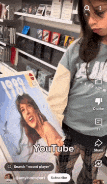 a girl in a blue shirt is holding a record that says 1989 on it
