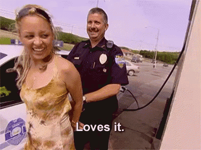 a woman in handcuffs is smiling next to a police officer who says loves it