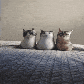 three cats sitting next to each other on a blanket