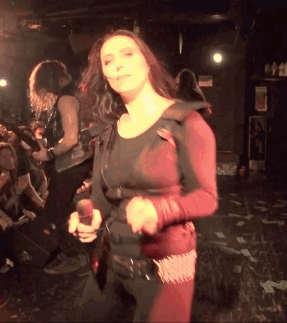a woman singing into a microphone while a man plays a guitar in the background