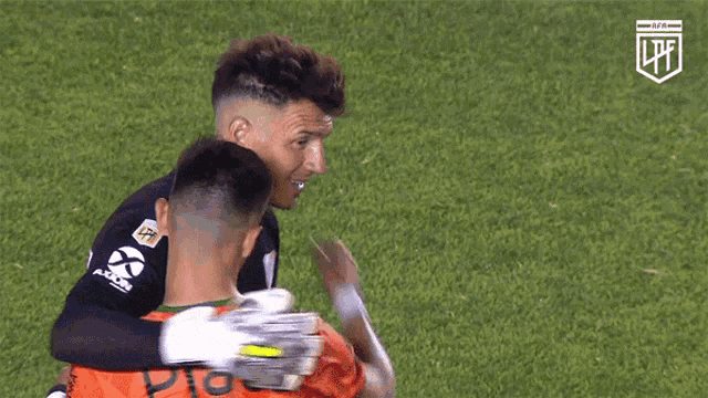 two soccer players are hugging each other on a field with a lpf logo in the corner