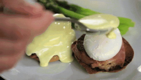 a person is spreading a yellow sauce on a sandwich
