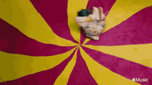a woman is laying on a colorful carpet in a spiral .