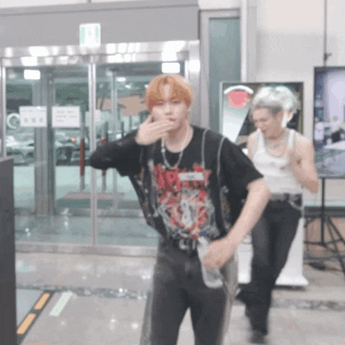 a man wearing a black shirt that says ' nirvana ' on it is standing in front of a glass door .