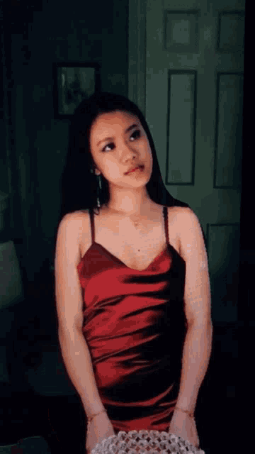 a woman in a red dress stands in front of a white door