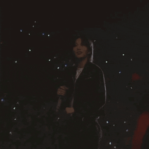 a man in a black leather jacket is singing into a microphone .