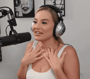 a woman wearing headphones and a white tank top is talking into a microphone