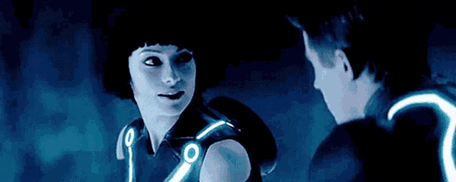 a man and a woman are looking at each other and the woman is wearing a vest with glowing lights on it