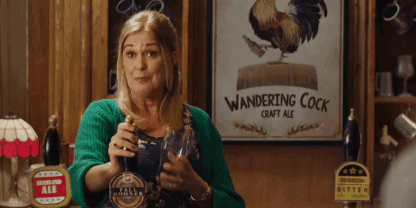 a woman holds a bottle in front of a sign that says wandering cock craft ale