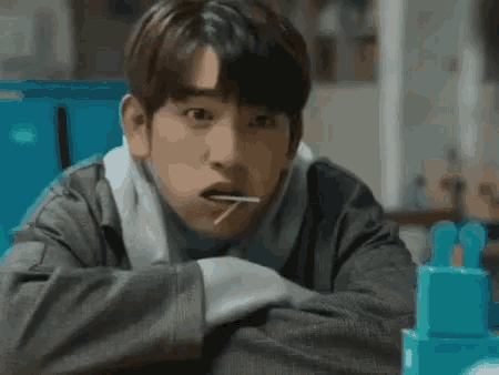 a young man is eating a candy bar with a stick in his mouth .