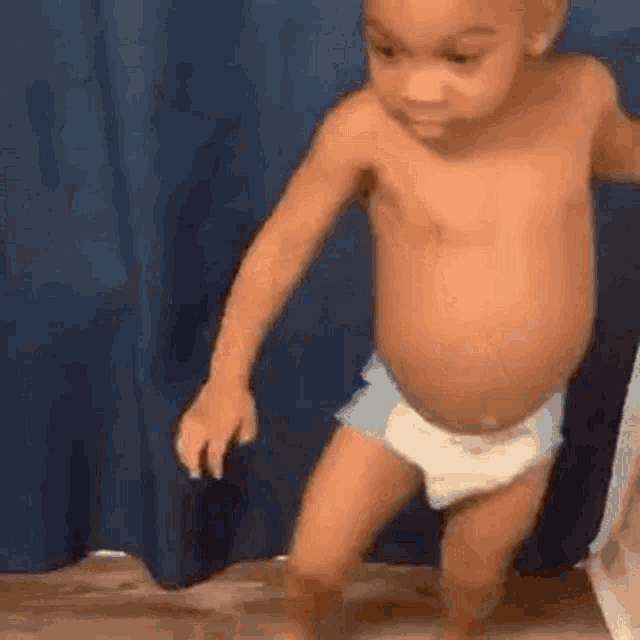 a baby in a diaper is walking in a room .