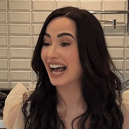 a woman with long black hair is smiling with her mouth wide open