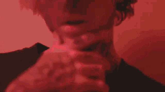 a close up of a person 's face in a red light with a red background .