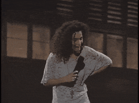 a woman singing into a microphone with a cross on her necklace