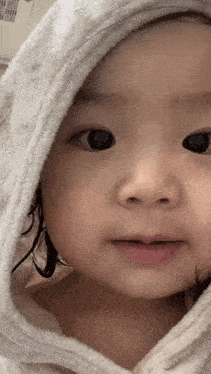 a baby girl wearing a white towel with a hood on her head .