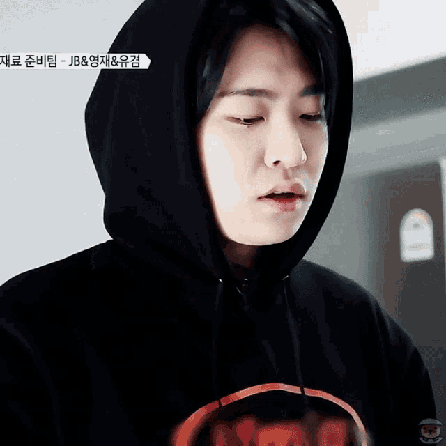 a close up of a person wearing a black hoodie with the word jb on the bottom right