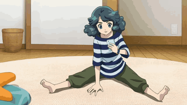 a girl in a striped shirt sits on the floor looking at her phone