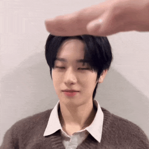 a person is putting their finger on a young boy 's head .