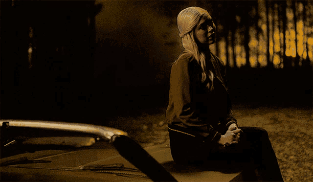 a woman is sitting on the hood of a car