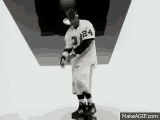 a man in a baseball uniform and shorts is standing in a room .