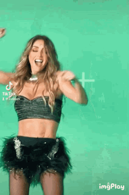 a woman is dancing in front of a green background with a tiktok logo