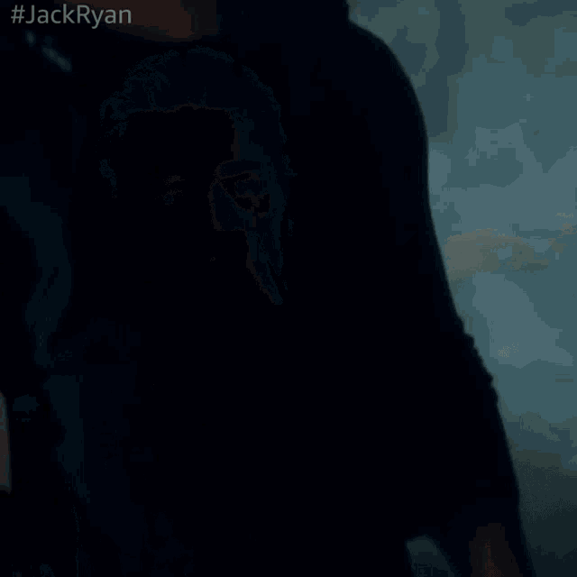 a man in a black shirt is holding a gun in a dark room with #jackryan written on the bottom