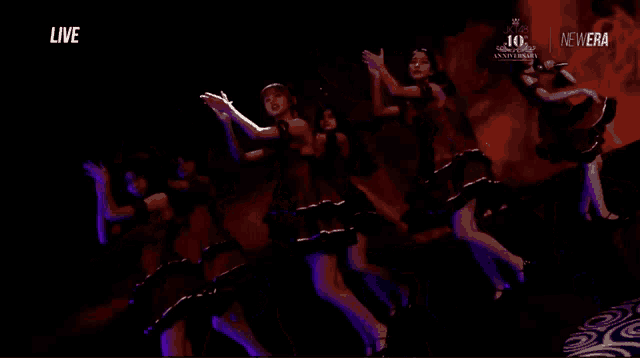 a group of women are dancing in front of a 10th anniversary banner