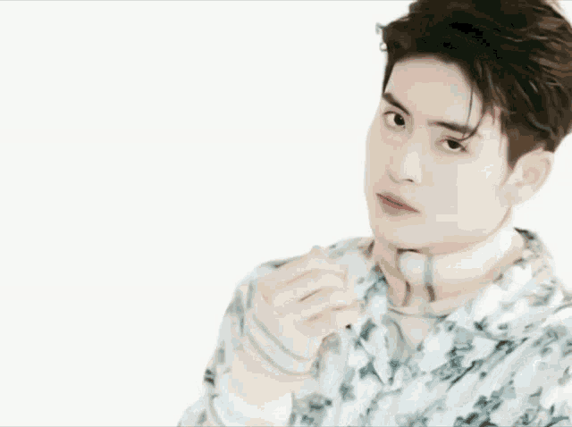 a young man wearing a floral shirt and a scarf looks at the camera