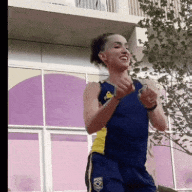 a woman wearing a blue tank top with a yellow emblem that says ' a ' on it