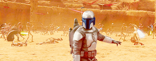 a man in a blue helmet is standing in a desert holding a lightsaber