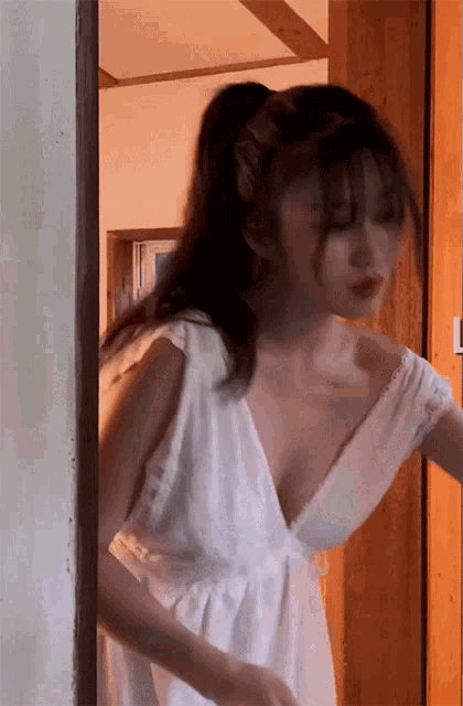 a woman in a white dress with a plunging neckline is standing in a doorway