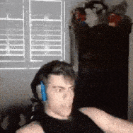 a man wearing headphones and a black tank top is sitting in front of a window