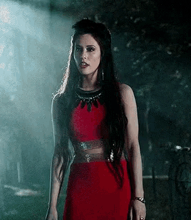 a woman in a red dress is standing in the dark .